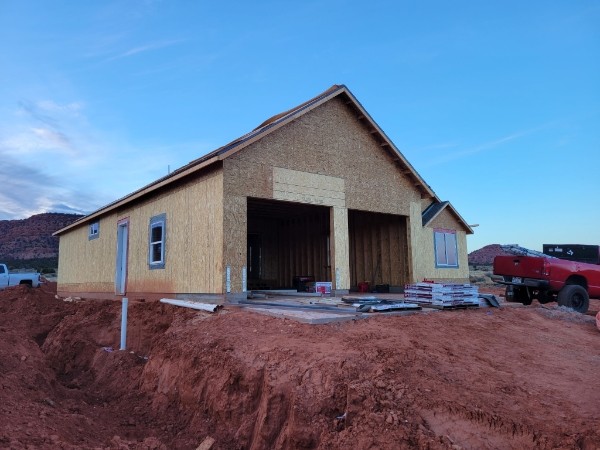 Three-quarter view of paired garage bays and red-soil site.